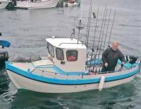 Этот капитан знает, где живет рыба. В его лодке два лосося